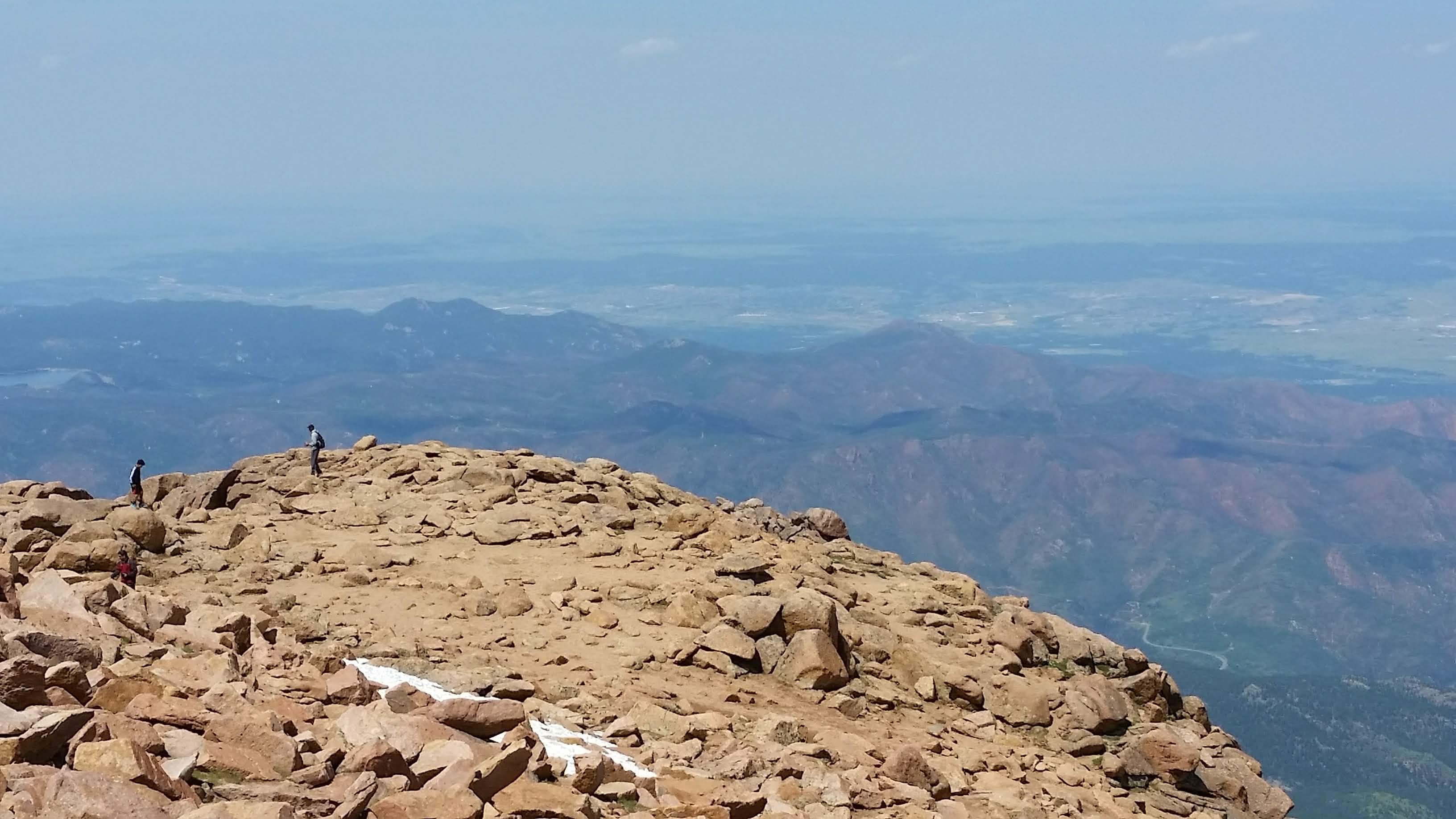 Hikers at the summit of a massive mountain.