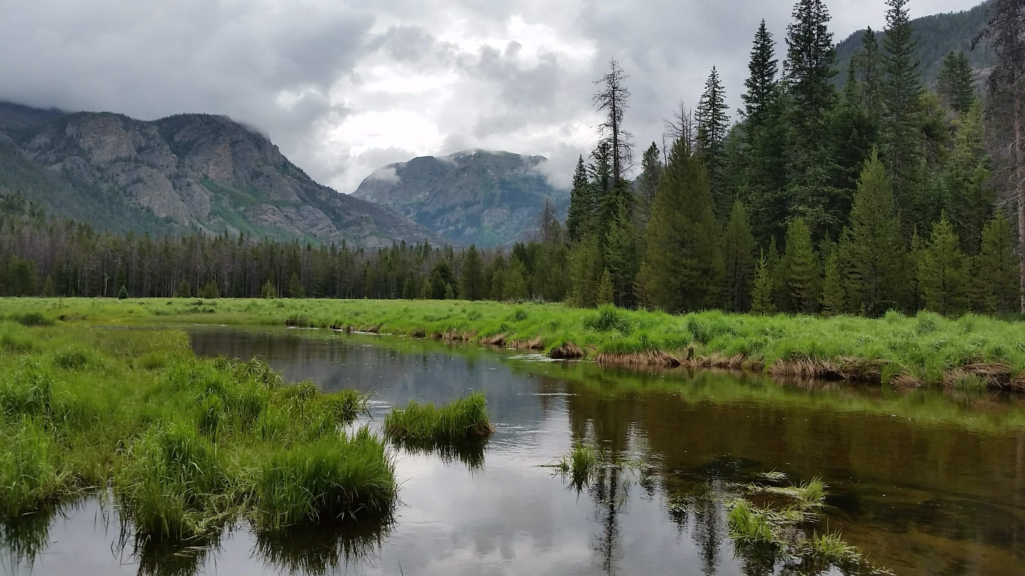 Mountains and a small alpine lake on a foggy day .
