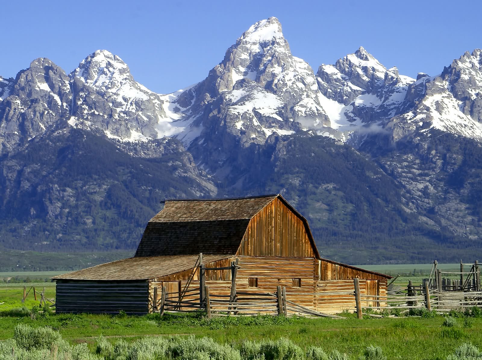 a cabin in front of the Teton Mountains.